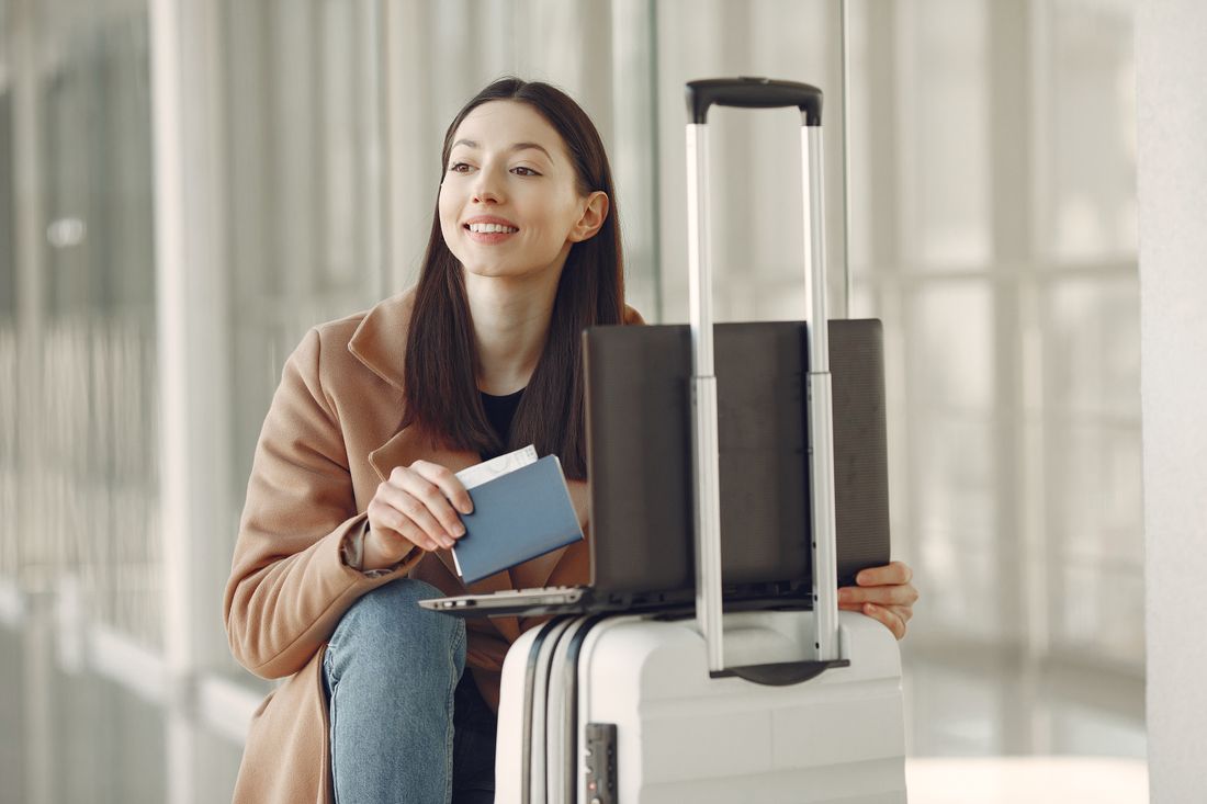 Traveler checking her laptop with her passport and luggage at the airport